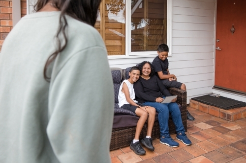 First nations family sitting together on couch outside - Australian Stock Image