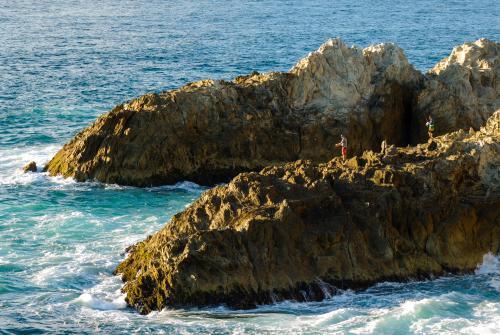 Fishermen far out on the rocks in the early morning light - Australian Stock Image