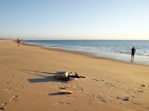 Fishing gear and fisherman on a remote beach - Australian Stock Image