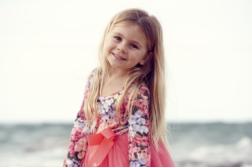 Five year old girl with blonde hair on beach looking back - Australian Stock Image