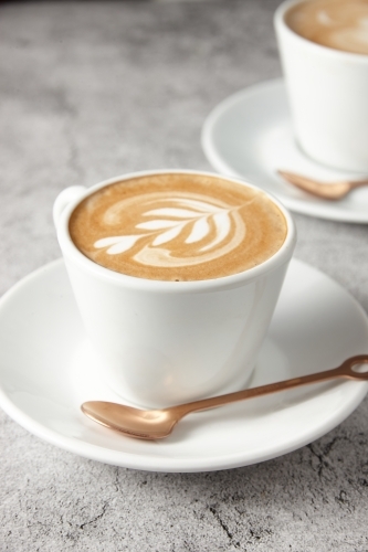 Flat white on saucer with spoon - Australian Stock Image