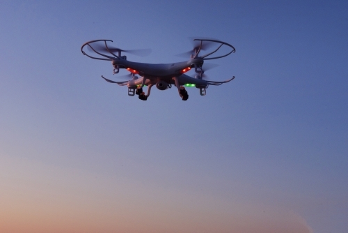 Flying drone in air at sunrise over mountain - Australian Stock Image