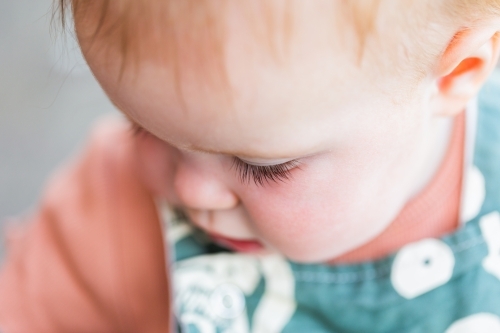 Focus on baby eyelashes while playing outside in overalls - Australian Stock Image