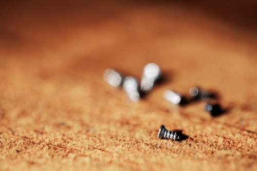 Focus on tiny screw on wooden tabletop - Australian Stock Image