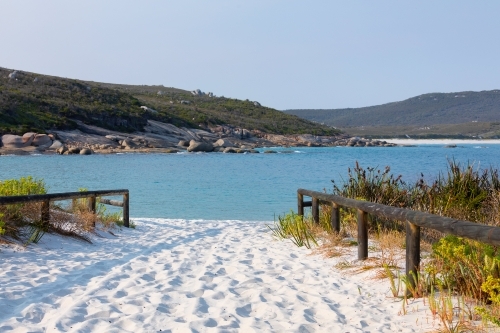 Footprints in white sand leading down to turquoise water at Bettys Beach near Albany - Australian Stock Image