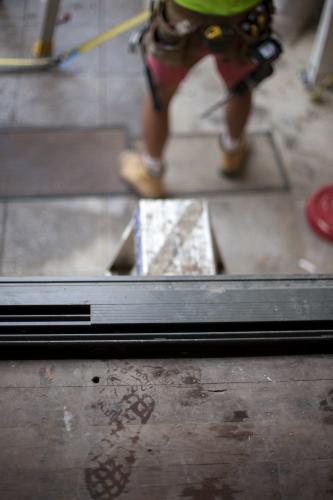 Footprints on wooden floorboards and tradesman working on deck at a home renovation site - Australian Stock Image