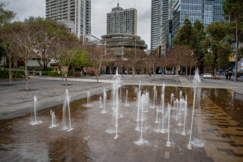 Fountain at Tumbalong Park with tall buildings in the background - Australian Stock Image