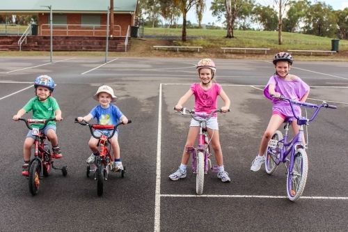 Four children on bikes smiling - Australian Stock Image