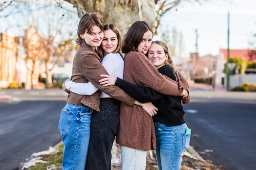 Four female friends hugging and smiling - Australian Stock Image