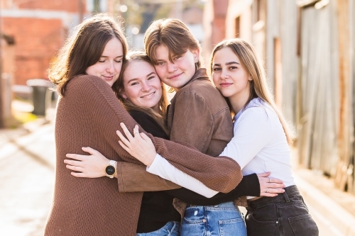 Four girls smiling and cuddling in alley - Australian Stock Image