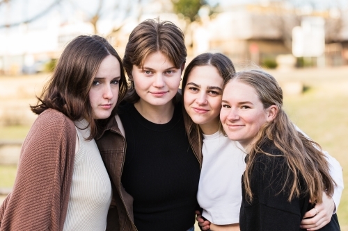 Four teen girls huddled together in park - Australian Stock Image