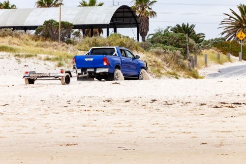 four wheel drive with boat trailer driving on sandy beach - Australian Stock Image