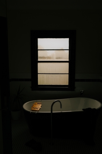 Freestanding bathtub with a wooden tray located near the window