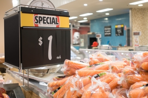 Fresh carrots $1 per 1kg bag, with special tag in supermarket - Australian Stock Image