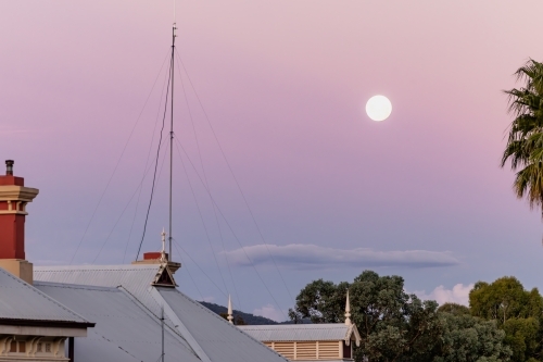 Full moon rising in pink and purple twilight sky - Australian Stock Image