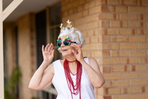 fun-loving elderly lady dressed up in reindeer antlers and fancy glasses at xmas
