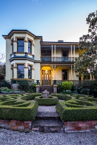 Gardens and light on porch of the historic Corinda accommodation in Hobart at night - Australian Stock Image