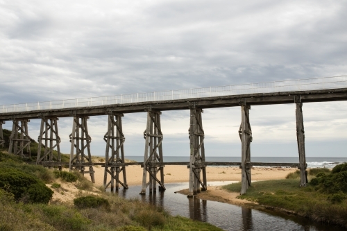 Gipplsand, Kilcunda Bourne Creek Trestle bridge on an overcast day with ocean in background - Australian Stock Image