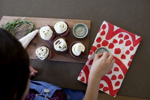 Girl decorating cupcakes in kitchen at home - Australian Stock Image