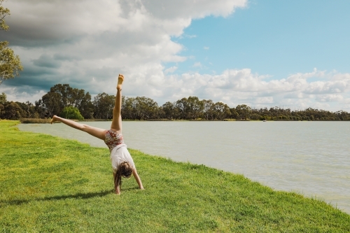 Girl doing cartwheel next to Lake in Boort, Victoria - Australian Stock Image