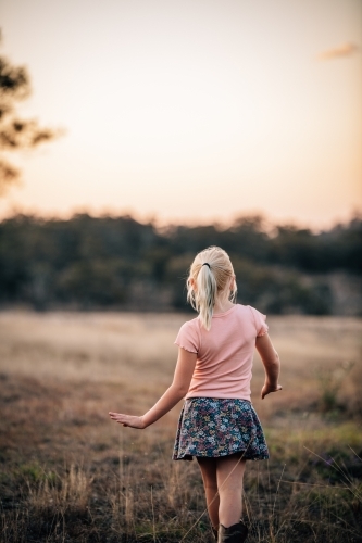 Girl facing into the landscape as she walks away - Australian Stock Image