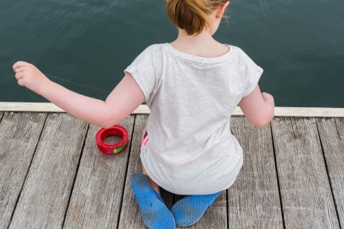 girl fishing with a hand reel from a wooden jetty