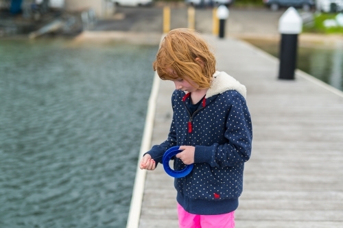 girl fishing with a hand reel from a wooden jetty - Australian Stock Image