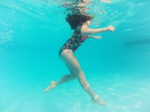 Girl floating underwater in a pool