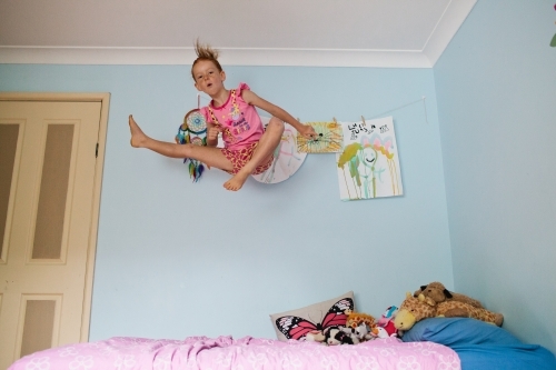 Girl jumping high on a bed