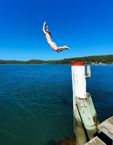 Girl jumping off a wharf - Australian Stock Image