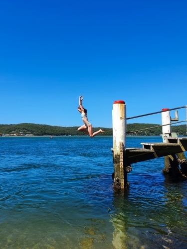 Girl jumping off a wharf - Australian Stock Image