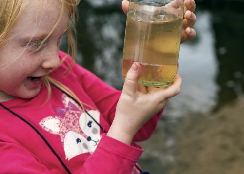 Girl Looking in Jar at Fish - Australian Stock Image