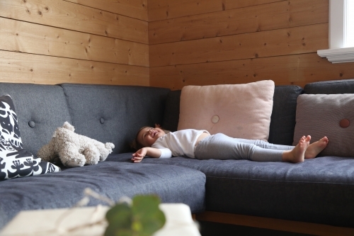 Girl lying on lounge laughing - Australian Stock Image