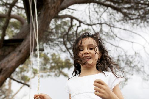 Girl playing outside with a rope swing - Australian Stock Image