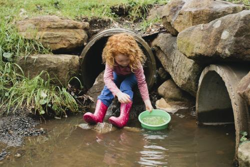 Girl playing with a bucket in the drain