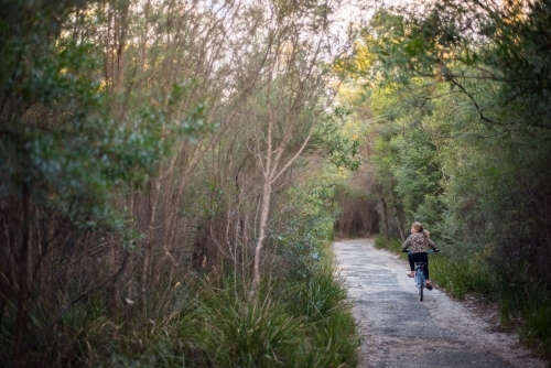 Girl riding bike along path in bush - Australian Stock Image