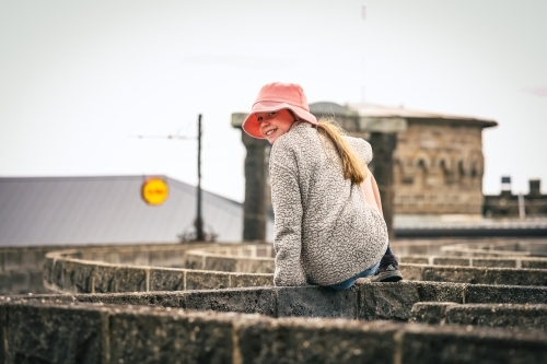 Girl sitting on maze wall at Kryal Castle, Ballarat Victoria Australia - Australian Stock Image