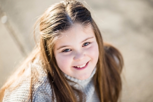 Girl sitting smiling looking up - Australian Stock Image