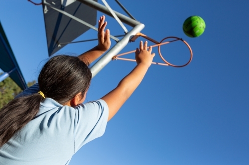 Girl throwing ball through goal hoop - Australian Stock Image
