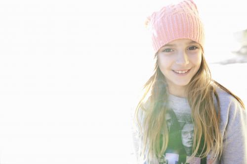 Girl wearing a beanie smiling with sunlight on background - Australian Stock Image