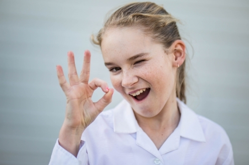 Girl winking while holding up fingers - Australian Stock Image