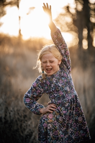 Girl with hand on hip and up in the air dancing in the sunshine - Australian Stock Image