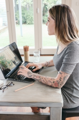 Girl working at home looking out the window thinking - Australian Stock Image