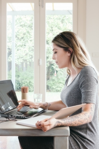 Girl working or studying at home with laptop and notebook - Australian Stock Image