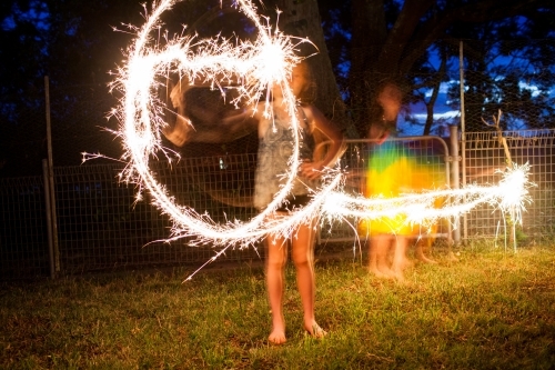 Girls making shapes with sparklers at night - Australian Stock Image