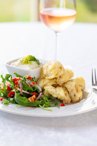 Golden-brown battered and fried meat with fresh salad and dip on the side. - Australian Stock Image