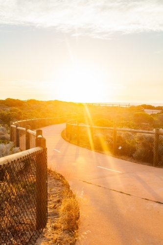 Golden sunlight shining over coastal walking path - Australian Stock Image