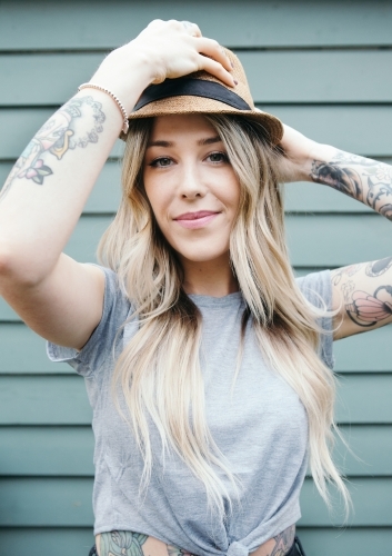 Gorgeous girl with long blonde hair putting on a summer hat - Australian Stock Image