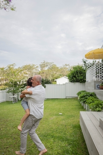 Grandad and grandson hugging in backyard - Australian Stock Image