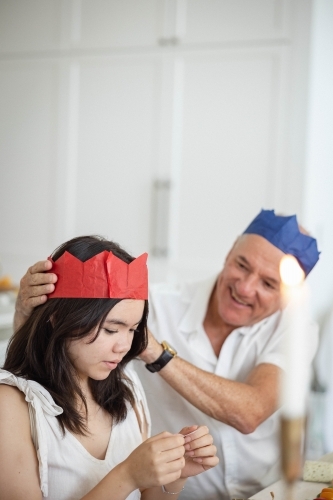 Grandad placing paper crown on granddaughter's head - Australian Stock Image